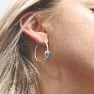 silver textured stud hoops with blue topaz on model