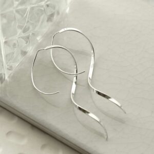 silver helix ribbon threader earrings strewn on tile