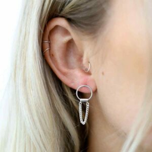 silver curb chain hanging from ring earrings on model