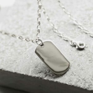 medium silver dog tag on white stone