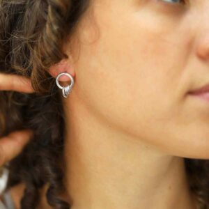 silver rings hanging on hoop stud earrings on model