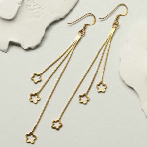 gold hanging stars dangly earrings laid on tile