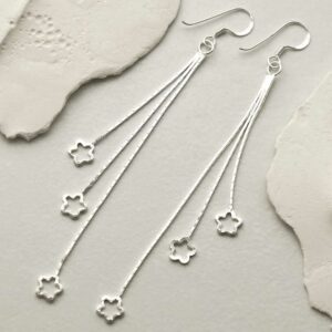 silver hanging stars dangly earrings laid on tile