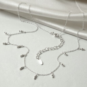 silver tiny lantern charms on chain strewn on cloth