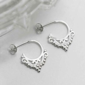 silver delicate floral pattern hoop studs laid on tile