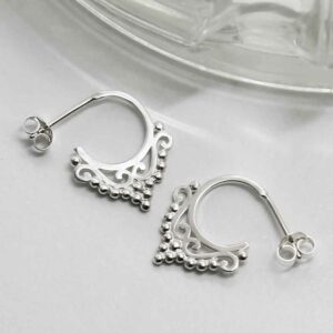 silver delicate floral pattern hoop studs strewn on tile