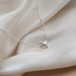 silver 3d cube pendant on chain on white cloth