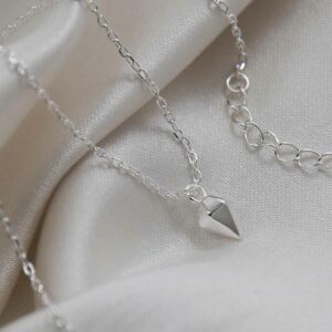 silver 3d diamond shaped pendant on chain on cloth