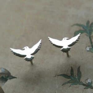 silver bird stud earrings on decorative paper