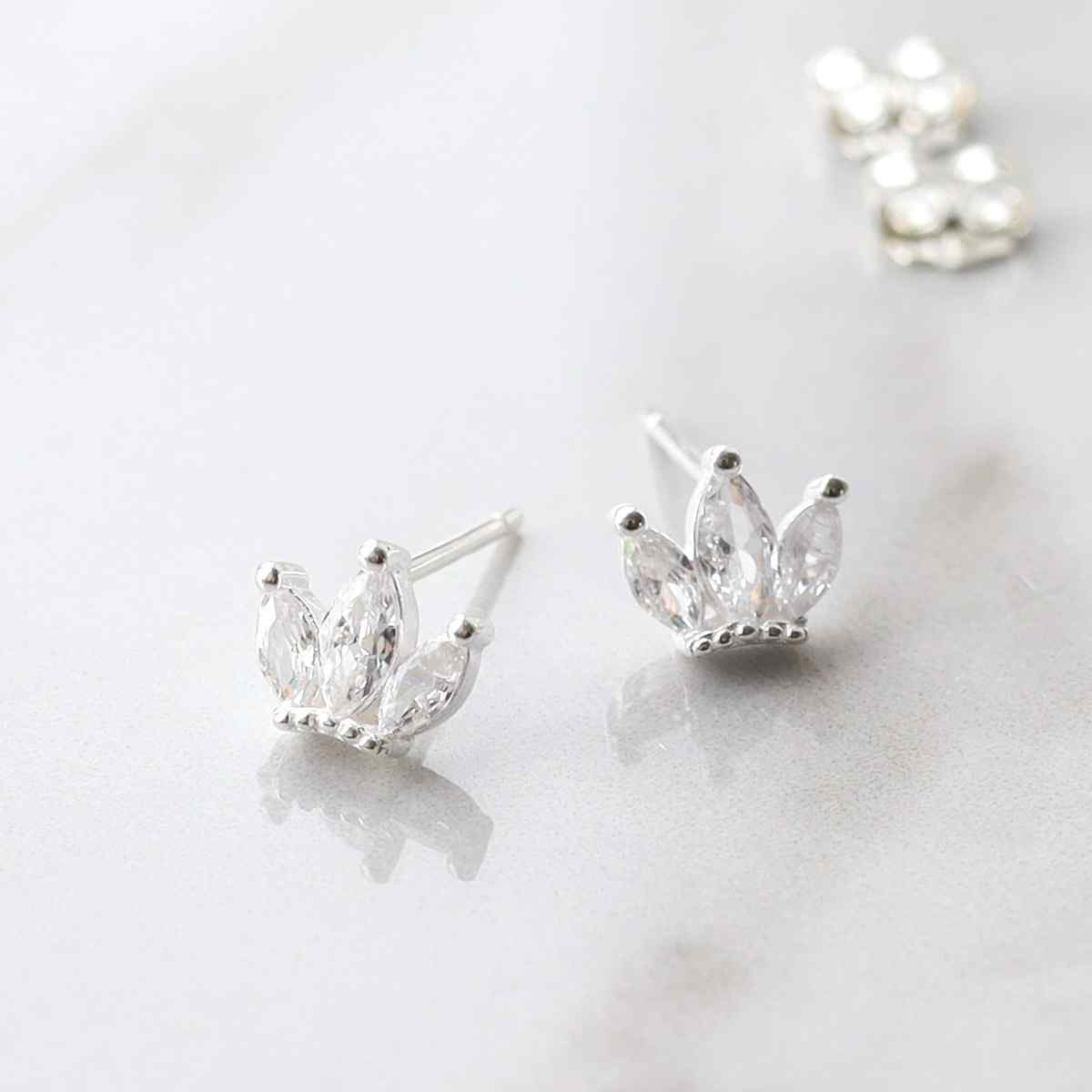 silver crown studs with cubic zirconia stone in centre on marble tile taken apart