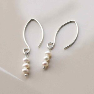 silver drop earrings with three hanging pearls on tile