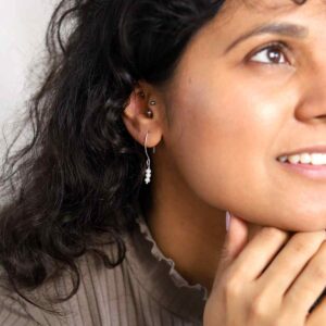 model wearing silver earrings with three dangly stacked pearls