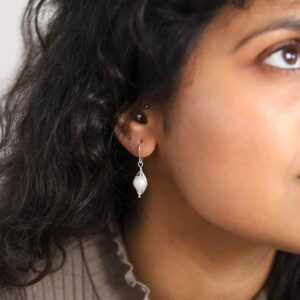 model wearing silver ellipse wire surrounding pearl earrings