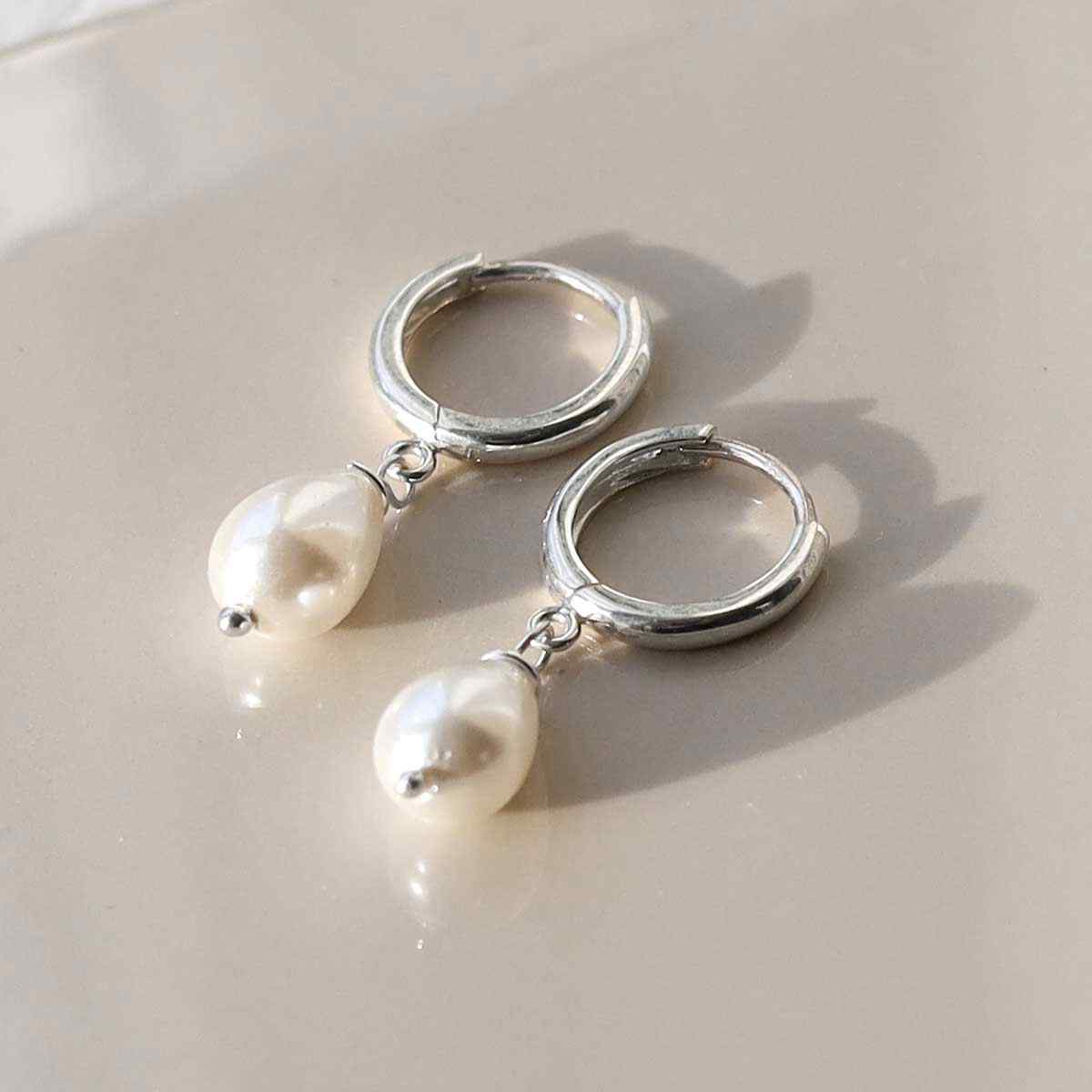 silver huggie hoops with a hanging pearl in shade