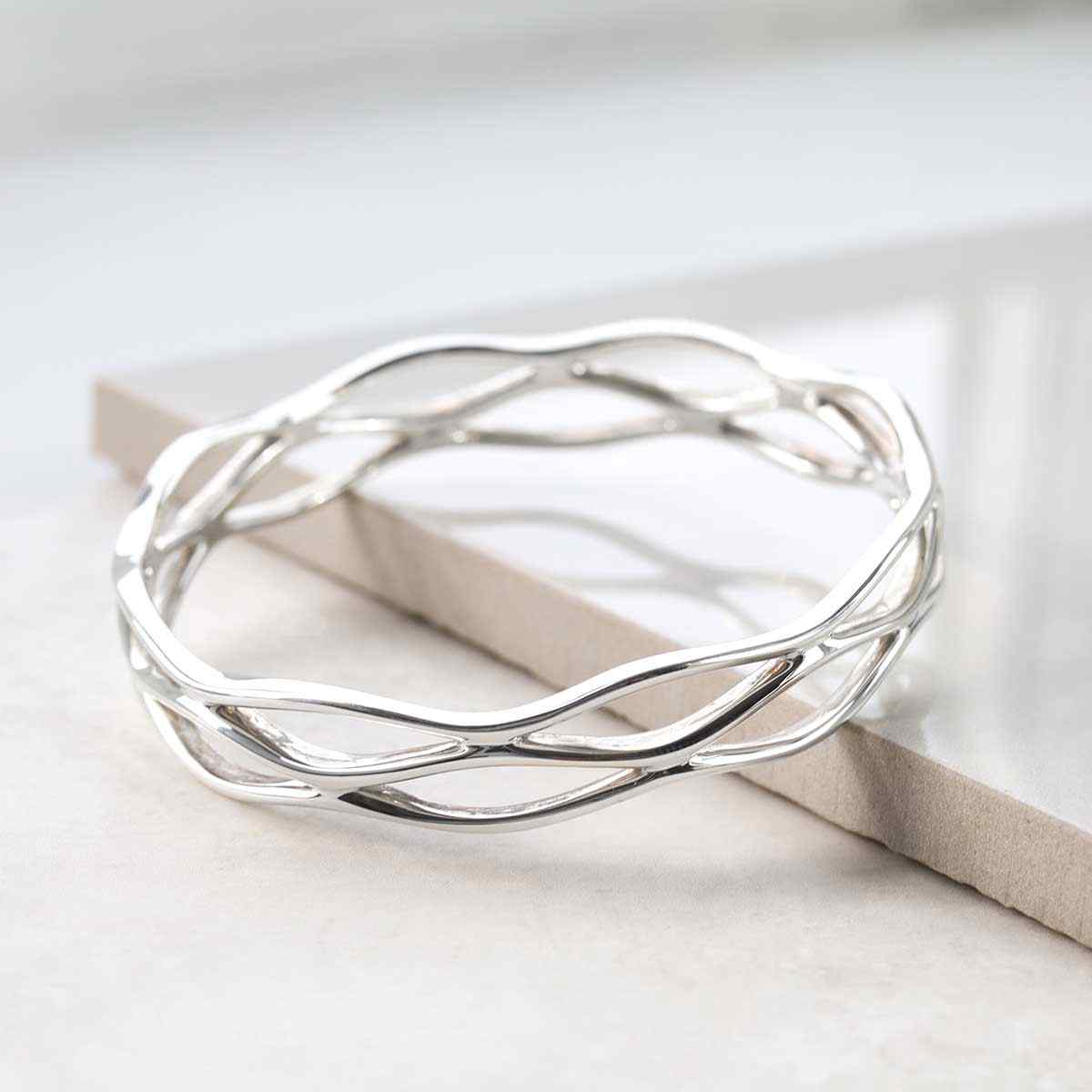 silver lattice net design bangle leaning on white tile