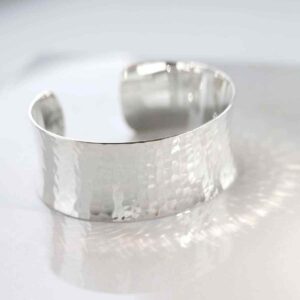 silver wide hammered cuff bangle reflecting light on white tile