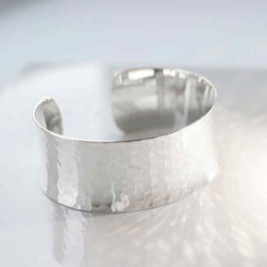 silver wide hammered cuff bangle reflecting light on white tile