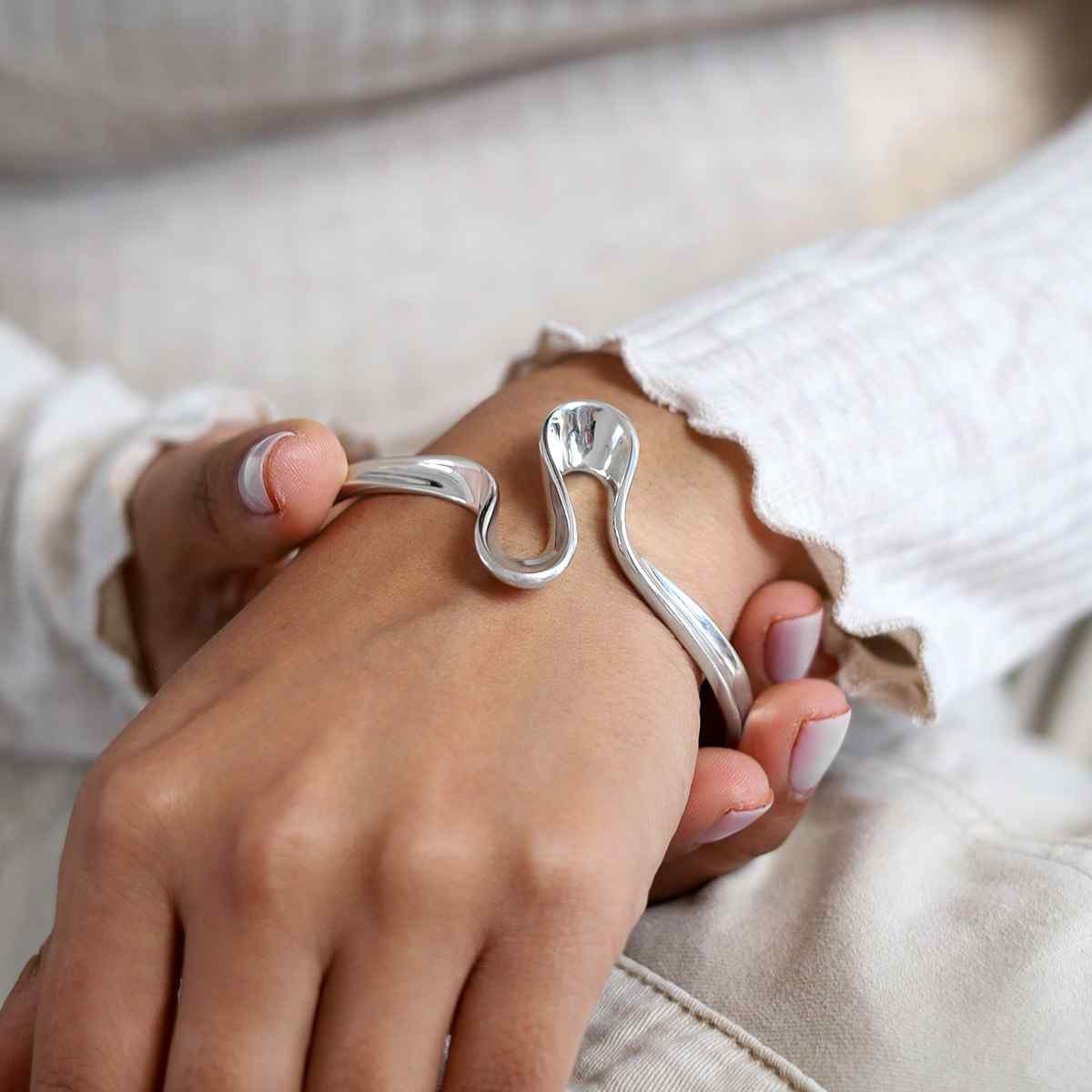 model wearing silver curling ribbon design bangle