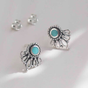 sterling silver ornate turquoise stud earrings on ceramic background