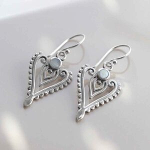 sterling silver mother of pearl arrow earrings on ceramic background