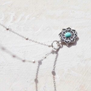 Turquoise moroccan flower necklace on ceramic and paint background