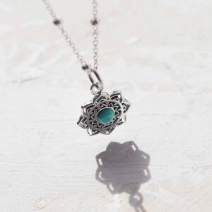 Turquoise moroccan flower necklace on ceramic and paint background