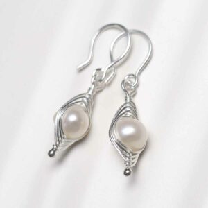 Sterling Silver Pearl Wire Dangly Earrings on textured ceramic background