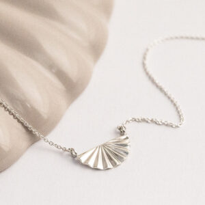 Sterling silver fan necklace on a white and shell background.