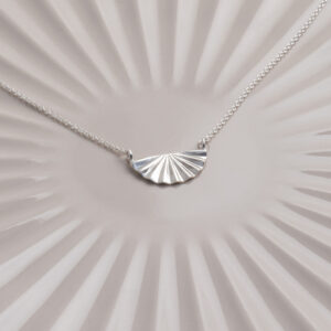 Sterling silver fan necklace on a white and shell background.