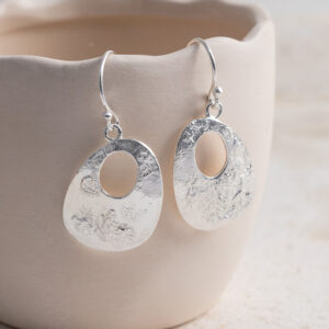 Sterling Silver Molten Dangly Earrings on a creamy cup prop background.