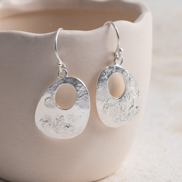 Sterling Silver Molten Dangly Earrings on a creamy cup prop background.