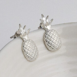 Playful sterling silver stud earrings shaped like pineapples, featuring fine detailing for a tropical, summery touch on a white cup background.