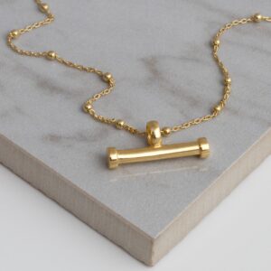 Gold plated Silver sterling silver T-bar necklace on a grey tile background, showing fine gold sterling silver ball chain and horizontal bar pendant.