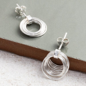 Sterling Silver Layered Hoops Studs on a sage green tile background.