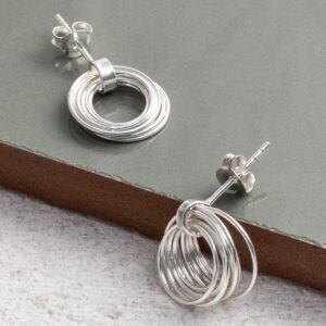 Sterling Silver Layered Hoops Studs on a sage green tile background.