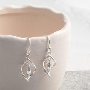 Sterling Silver Twirl Dangly Earrings on a cream wavy cup prop.
