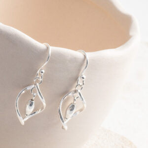Sterling Silver Twirl Dangly Earrings on a cream wavy cup prop.