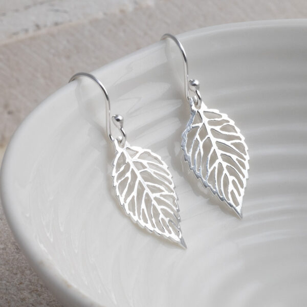 Sterling Silver Leaf Dangly Earrings earrings on a white shell background.