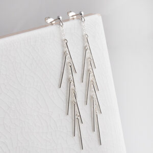 Sterling Silver Dancing Bar Studs on white tile background.