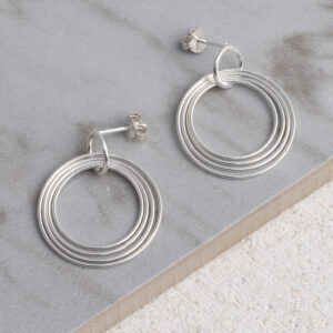 Sterling Silver Hoola Hoop Studs on a grey tile background.