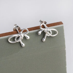 Sterling Silver Bow Studs on a sage green background.