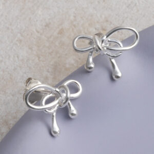 Sterling Silver Bow Studs on a purple tile background.