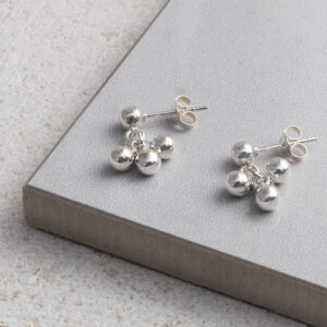 Sterling Silver Ball Bell Dangly Studs on a grey and white tile background.