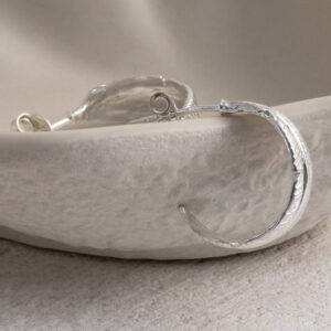 Sterling Silver Feather Hoop Studs on a cream background.