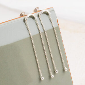 Sterling Silver Curved Bar Studs on a sage green tile background.