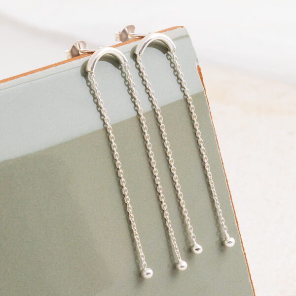 Sterling Silver Curved Bar Studs on a sage green tile background.
