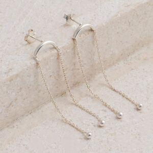 Sterling Silver Curved Bar Studs on a creamy tile background.