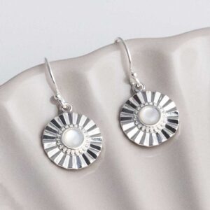 Sterling silver Mother of Pearl sun disc earrings set on a shell background.