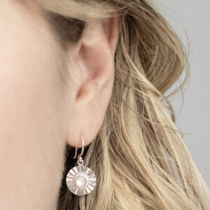Sterling silver Mother of Pearl sun disc earrings model shot.