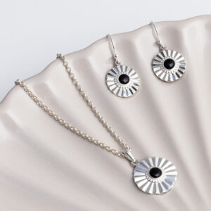 Sterling silver Onyx sun disc earrings and necklace set on a shell background.